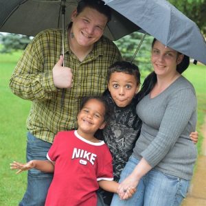 family of 4 under an umbrella
